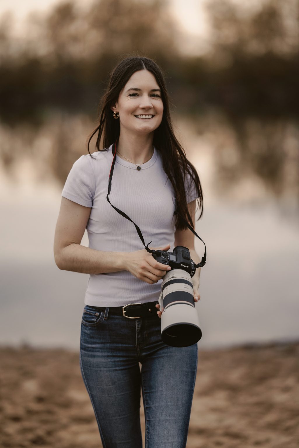 Lachende Fotografin mit Kamera am See